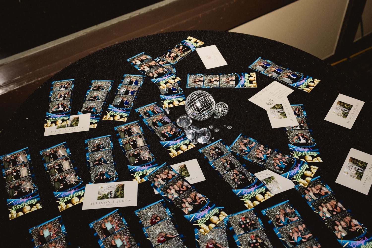 Multiple printed photo cards scattered across a dark wooden surface.