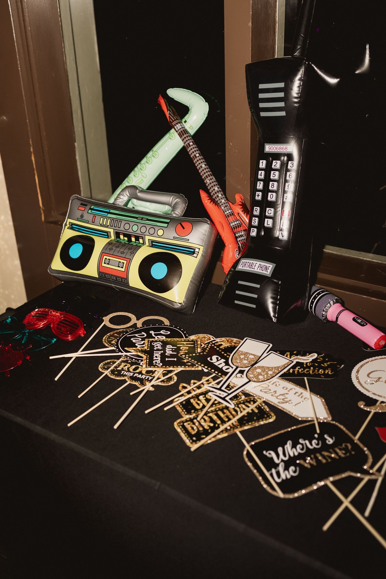 Party props including a retro boombox, phone, and name cards arranged on a black table.