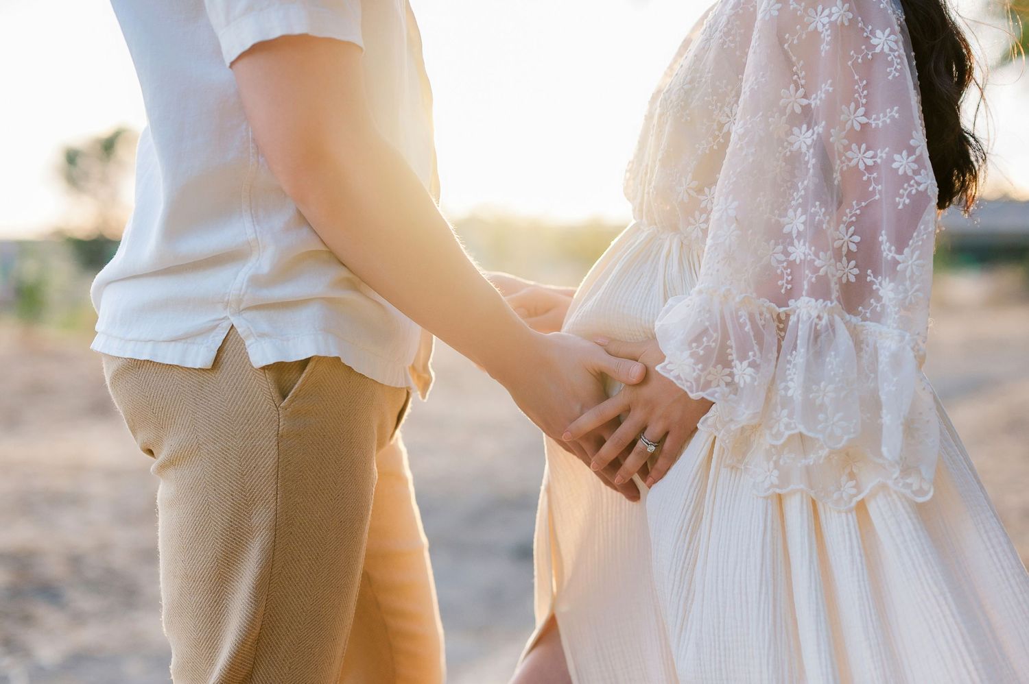Close-up shot of couple holding hands at a romantic sunset wedding ceremony.