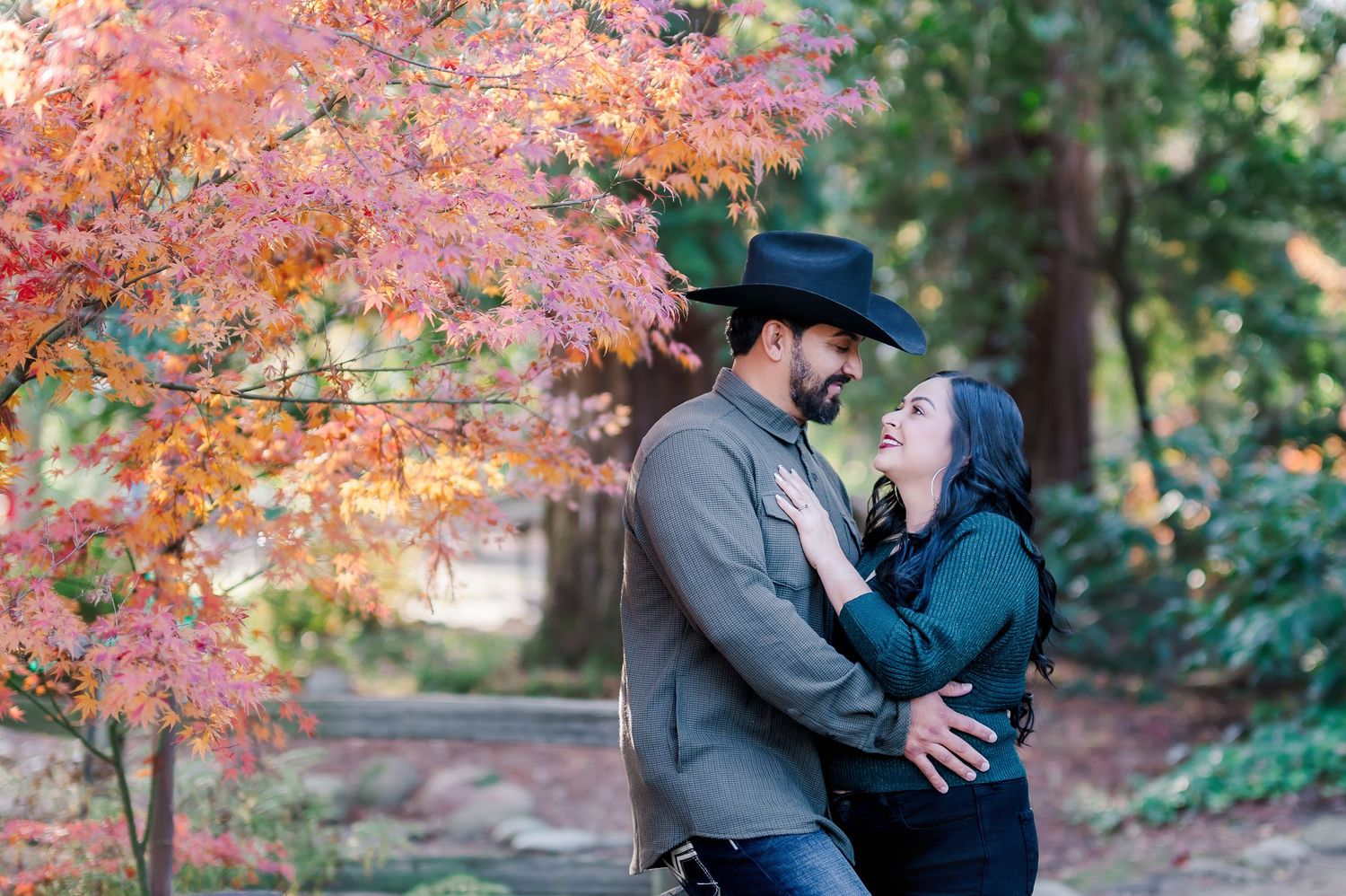 Romantic couple embracing under vibrant autumn foliage in a park setting.