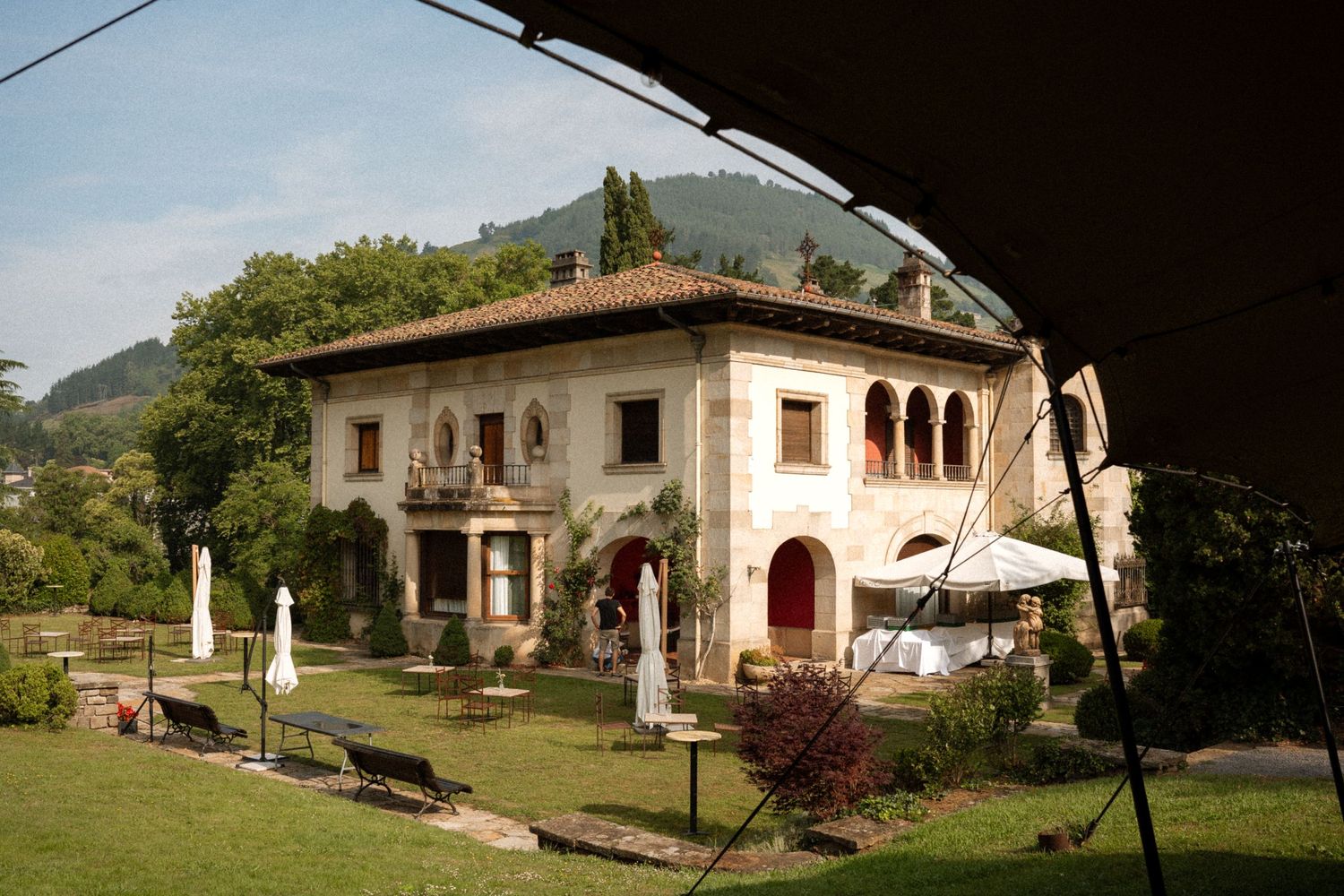A Mediterranean-style villa with arched windows and columns set against a hillside landscape.
