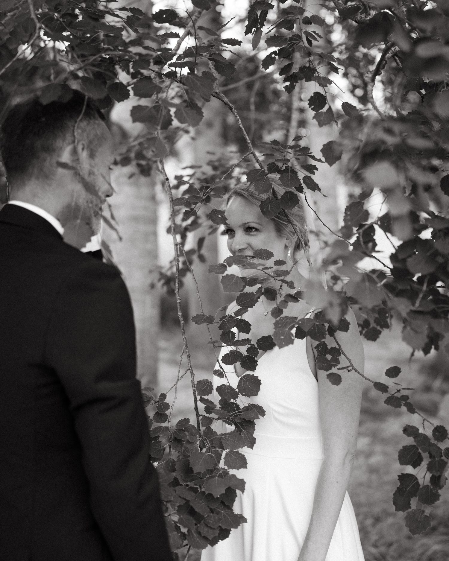 Romantic black and white portrait through leaves and branches.
