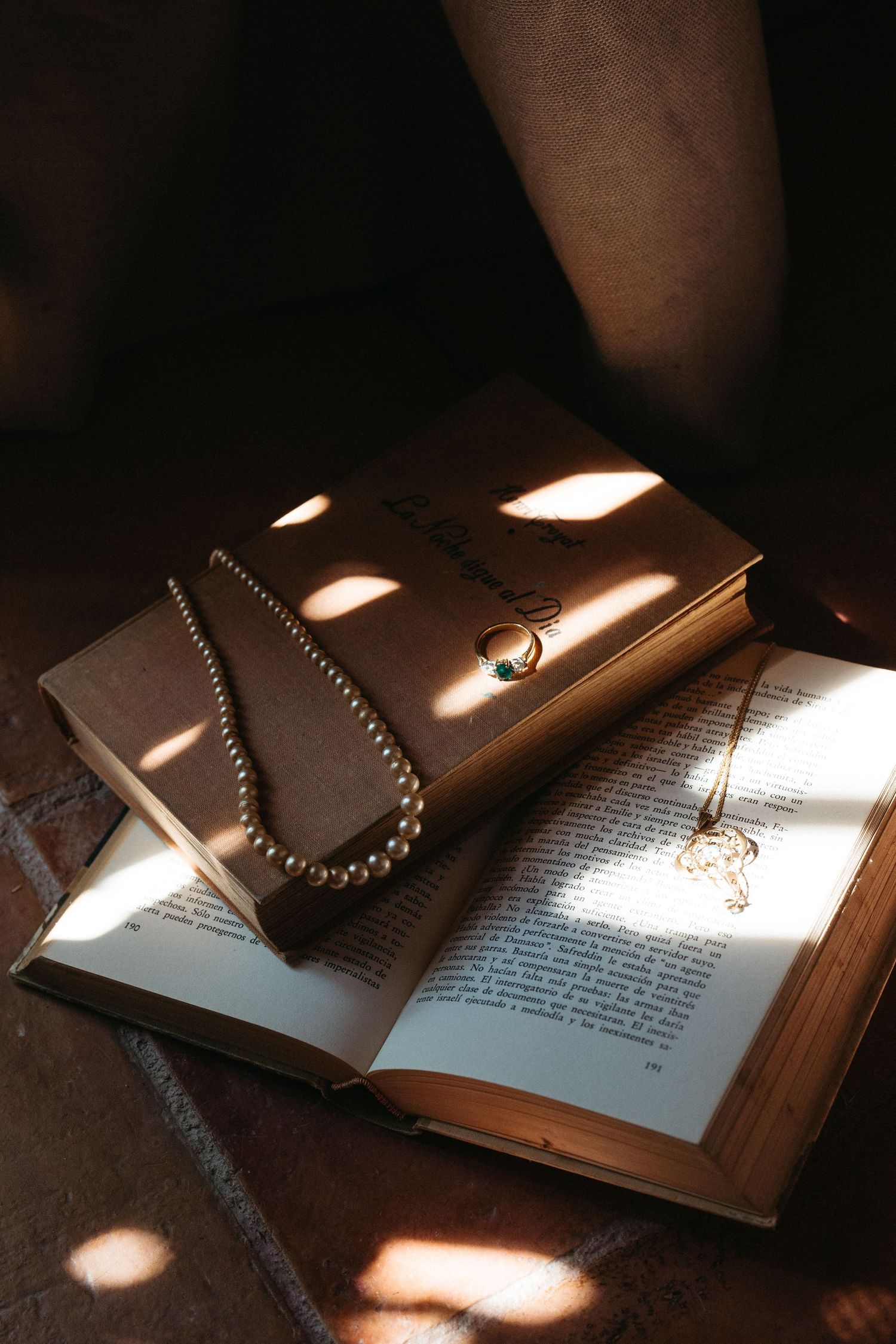An open book with necklace and leather wallet in dramatic lighting.