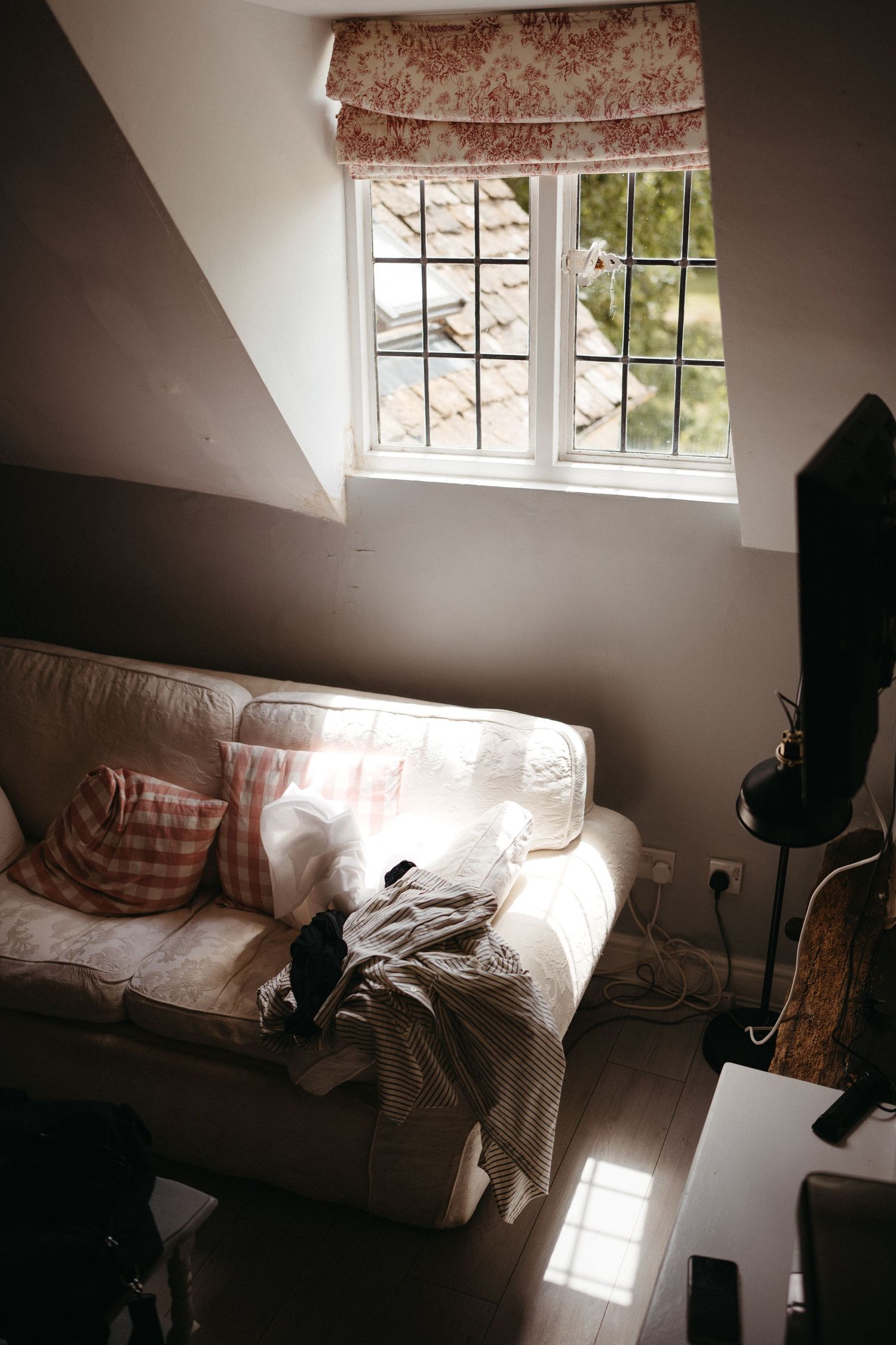 Cozy living room corner with window seat, floral roman shade and natural light streaming in.