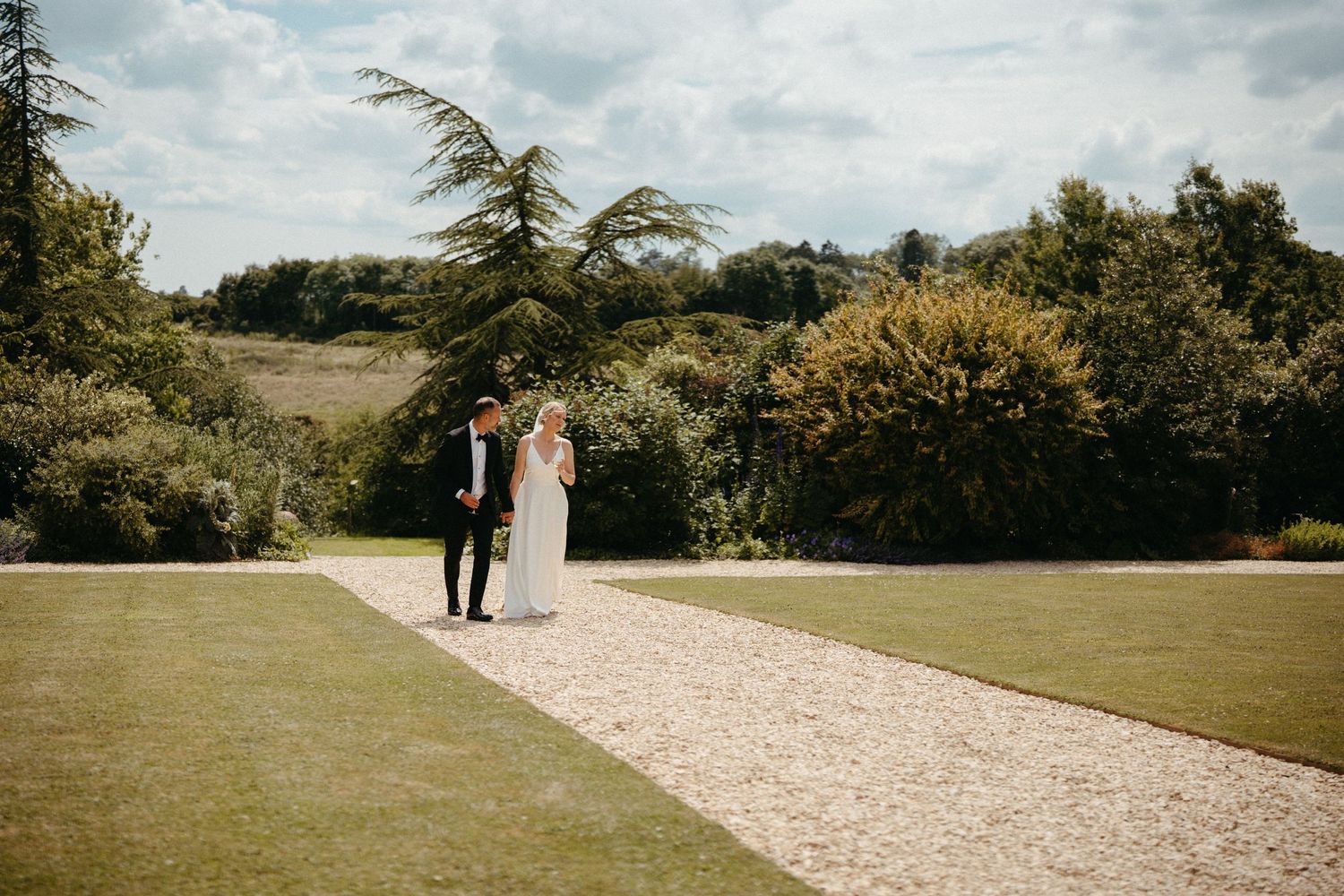 Couple walking along a garden path surrounded by lush greenery.