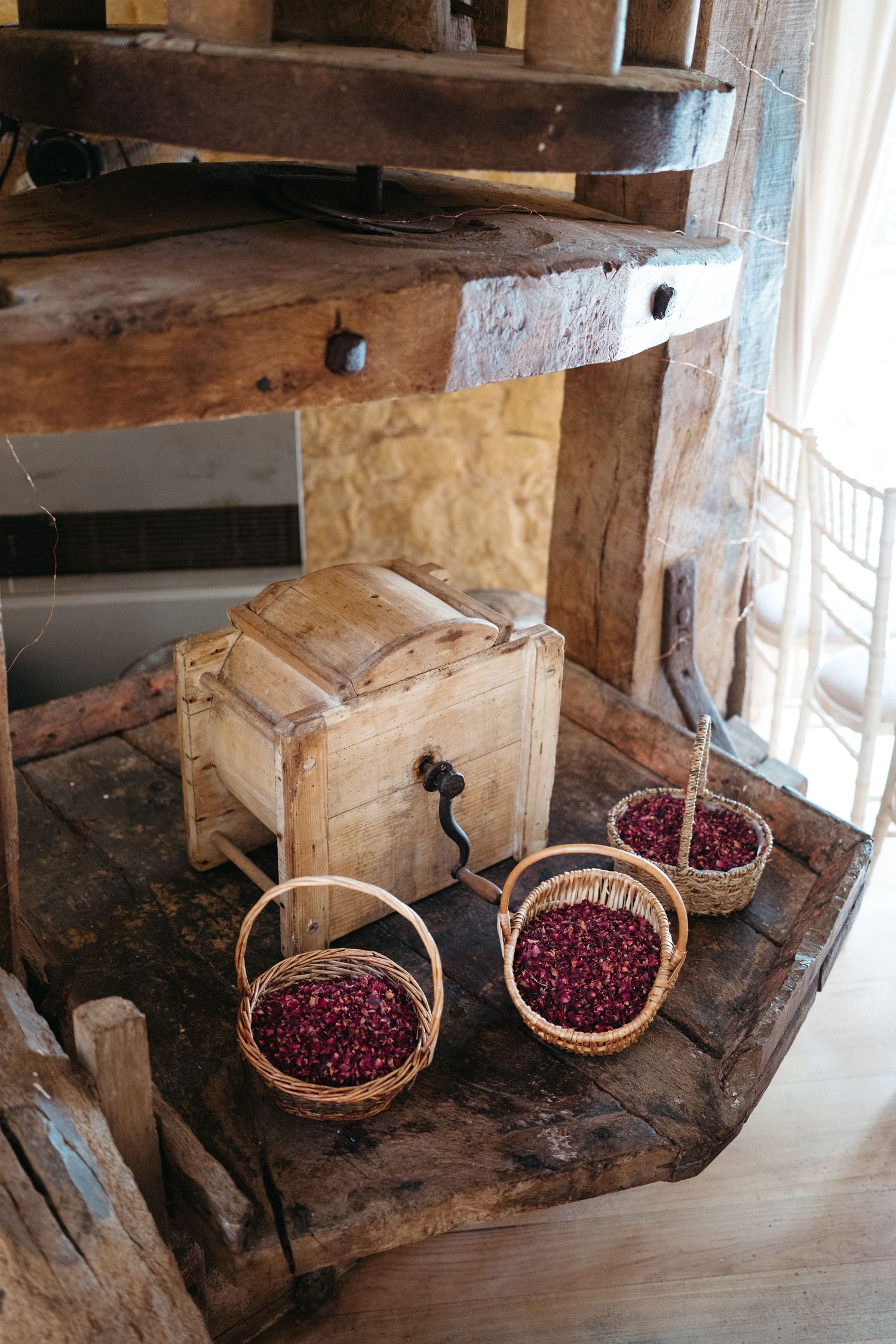 Rustic wooden shelf with vintage box and two baskets of fresh cranberries beside a window.