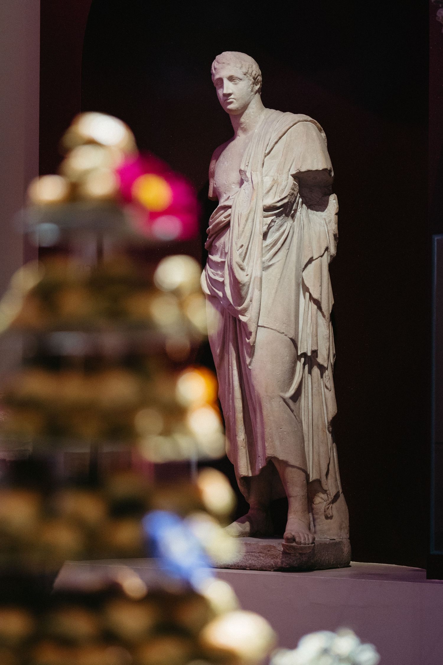 Classical marble statue displayed in museum with ornate decorations in foreground.