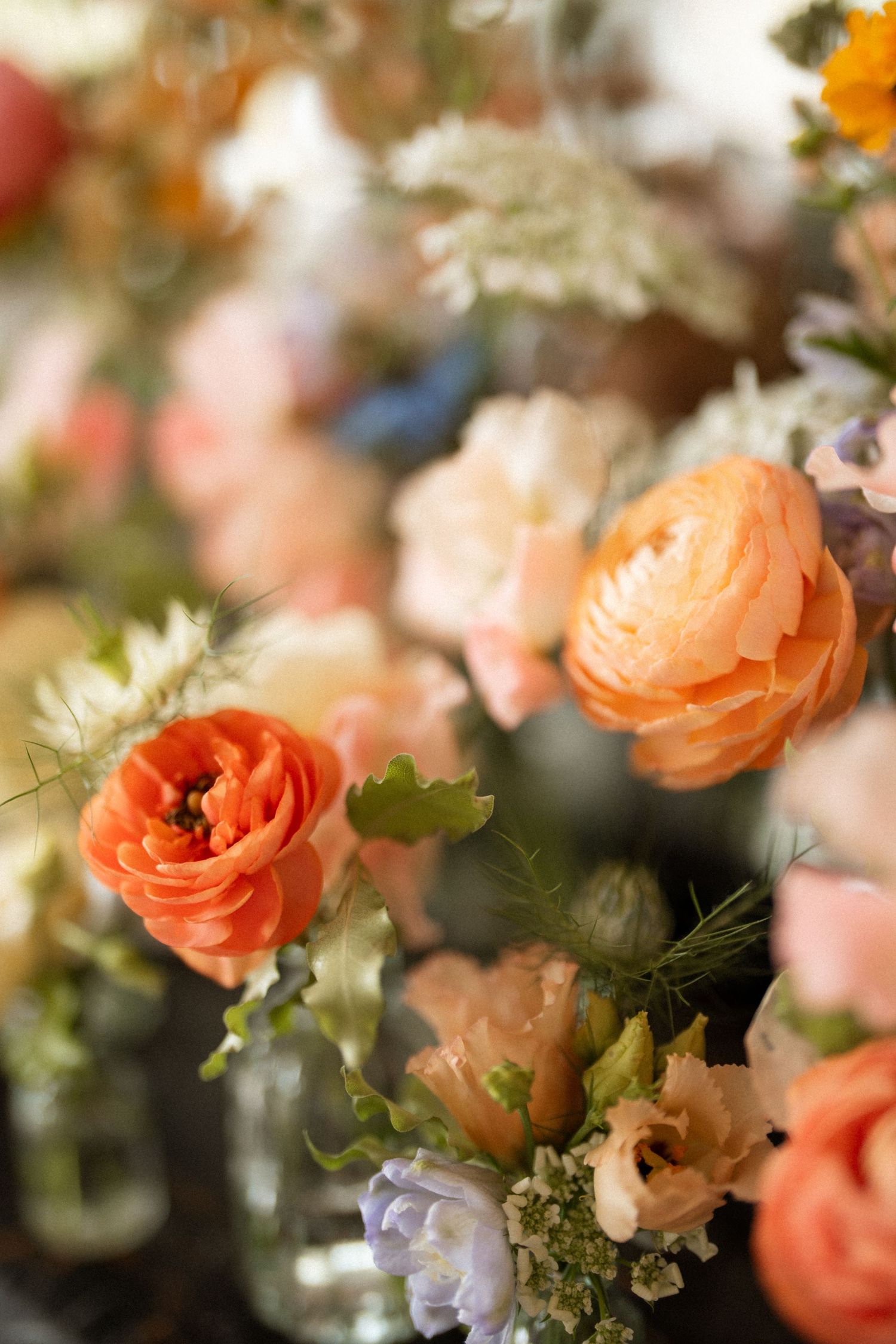 Orange and peach roses with delicate white flowers create a romantic floral arrangement with soft bokeh effect. Nonsuch mansion wedding