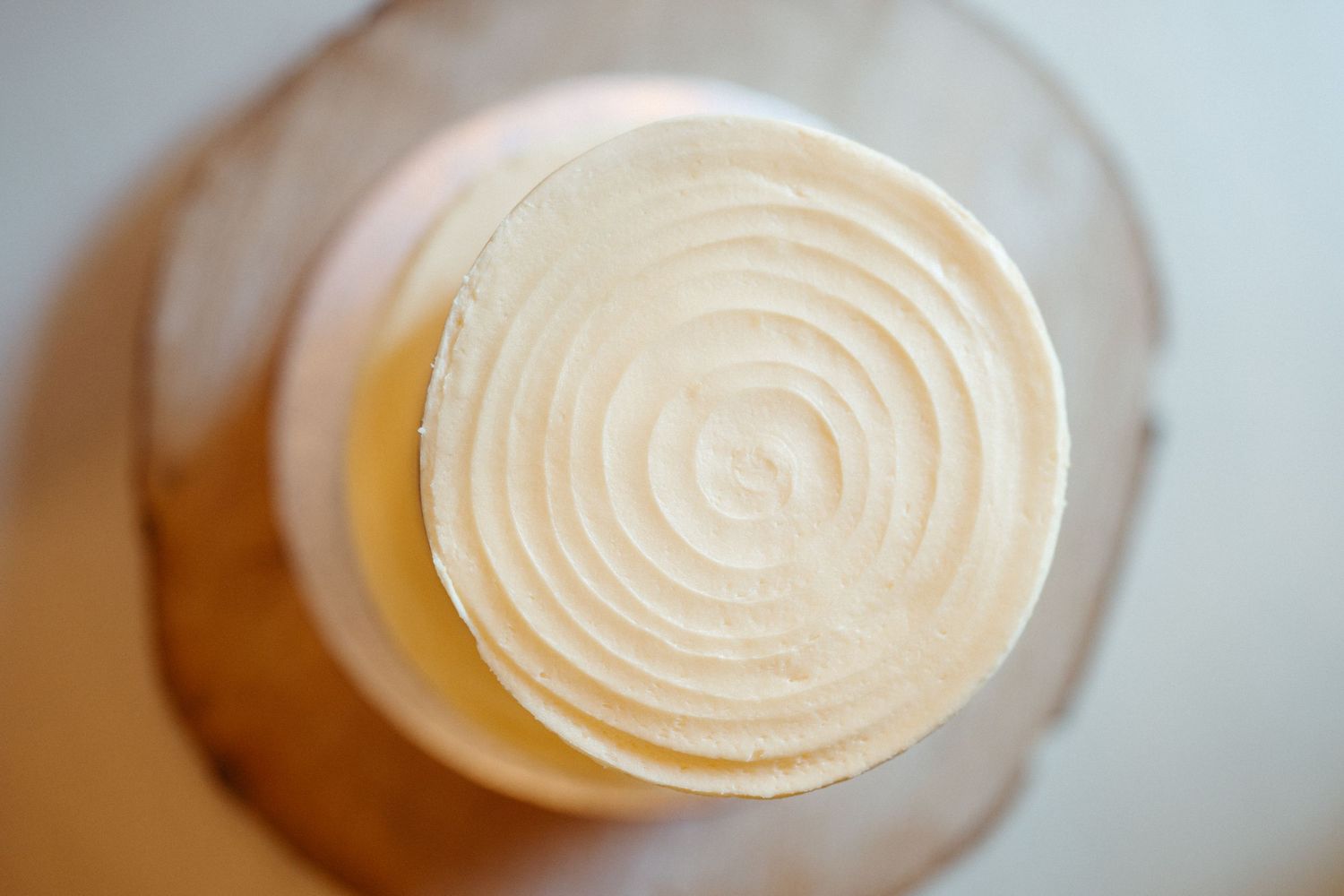 Overhead view of creamy white frosting swirled in concentric circles on top of a dessert.