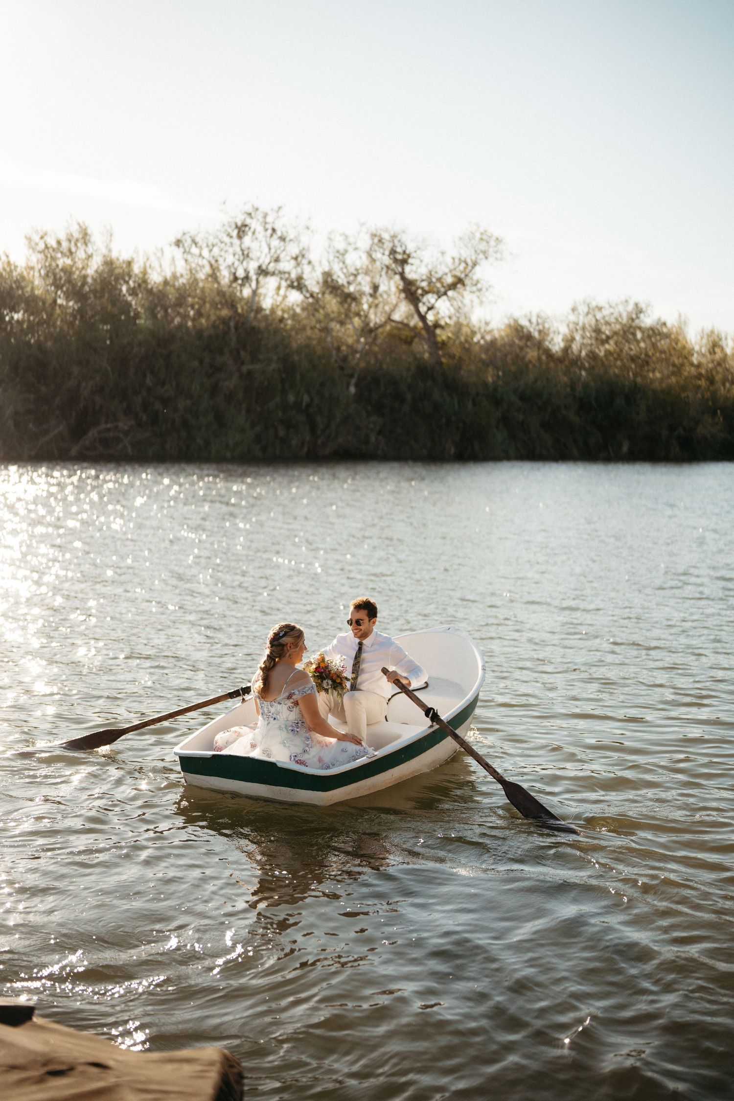 Romantic boat ride on calm waters during sunset with trees in background.