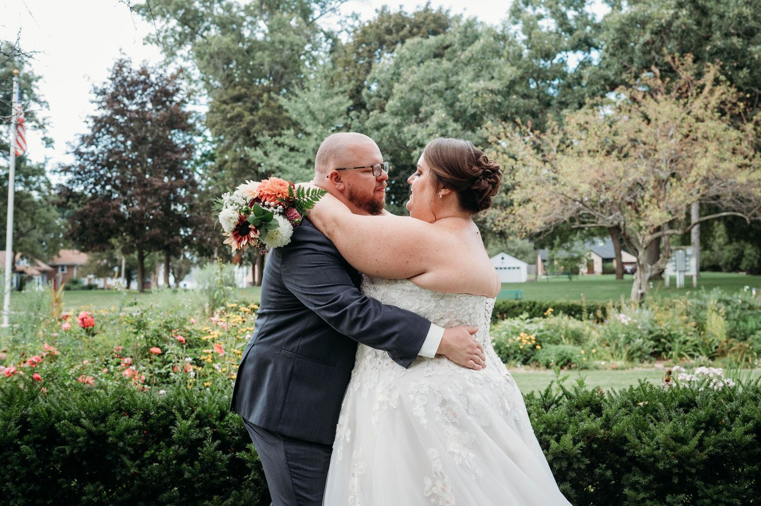 A romantic embrace between newlyweds in a lush garden setting with blooming roses and greenery.
