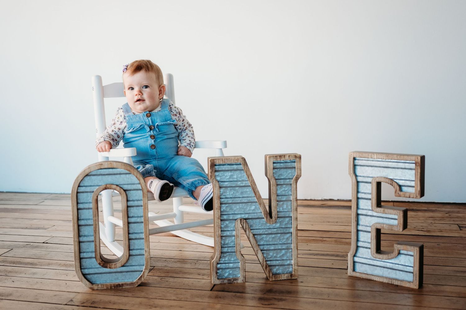 A panoramic sequence shows ONE text letters arranged on a wooden floor with a child in blue clothing.