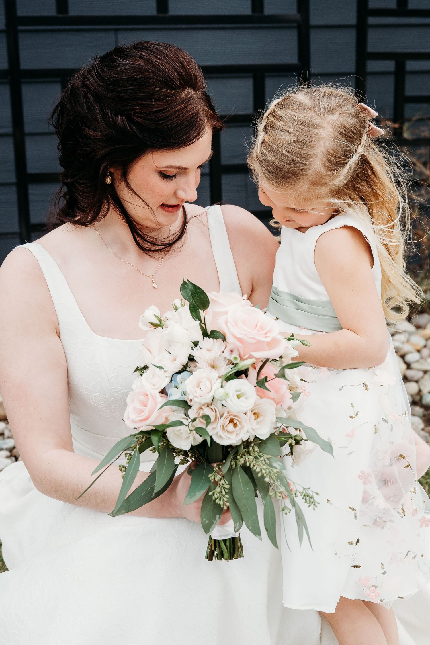 Tender moment at wedding with white bouquet of roses and eucalyptus featuring soft pink blooms and greenery.