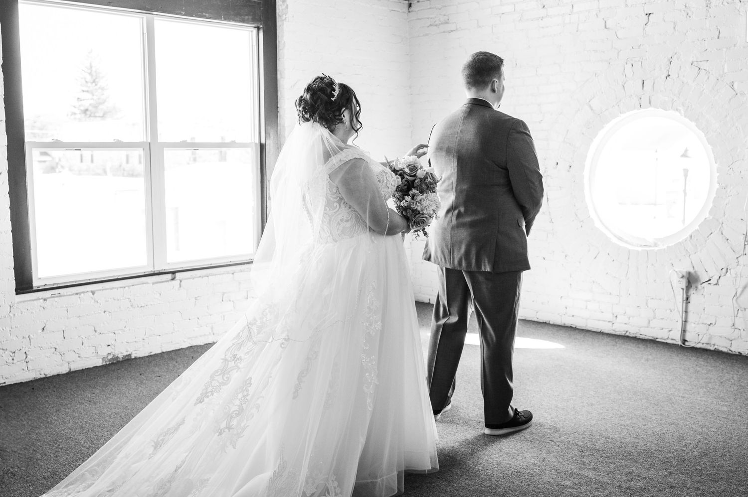 A couple shares a private first look moment in a sunlit room before their wedding ceremony.