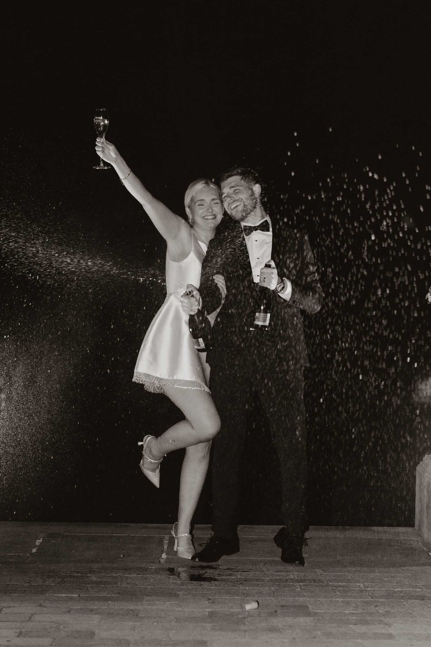 Black and white photo of a celebratory moment with champagne and falling sparkles at a formal event.