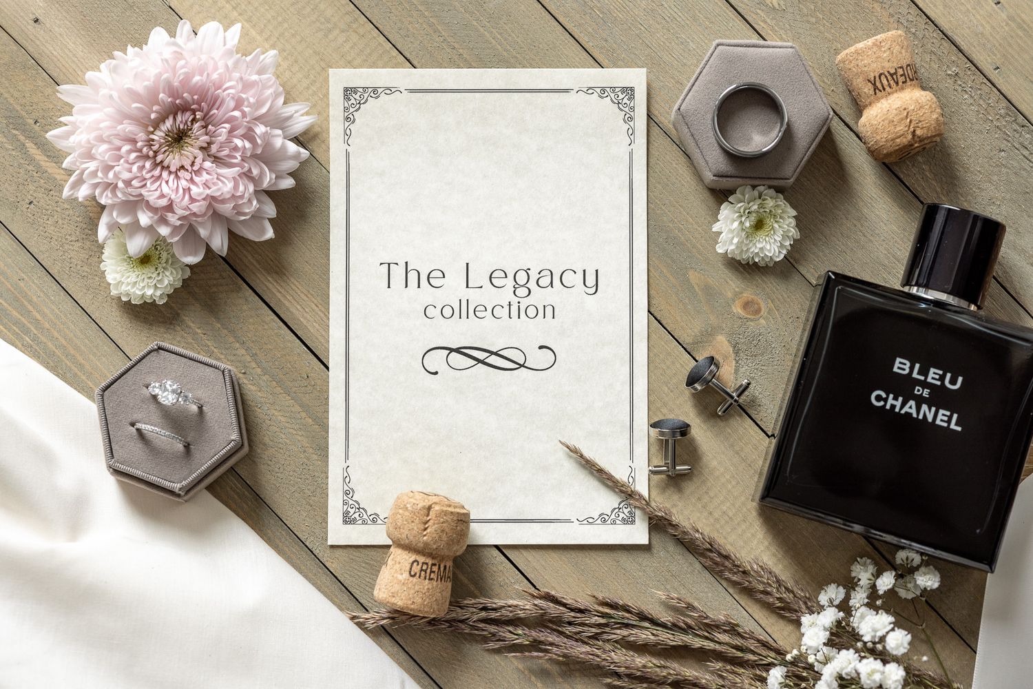 Pink flowers, Chanel perfume bottles, and decorative items arranged in a flat lay composition on wooden background.