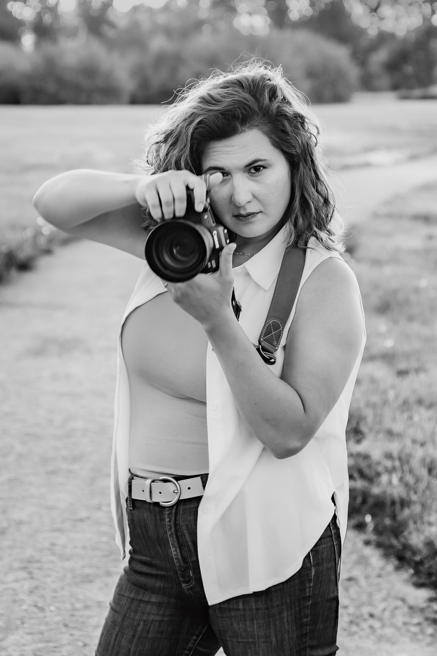 A photographer taking a photo outdoors with a professional camera in a black and white artistic portrait.