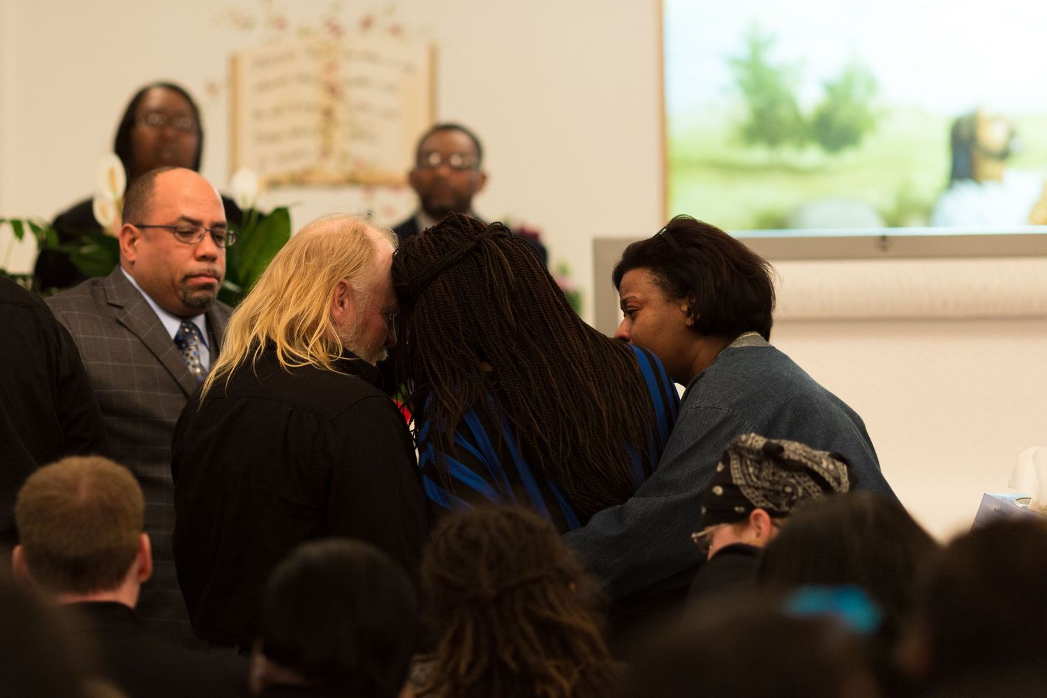 A group of people gathered closely together in discussion during what appears to be a classroom or meeting setting.