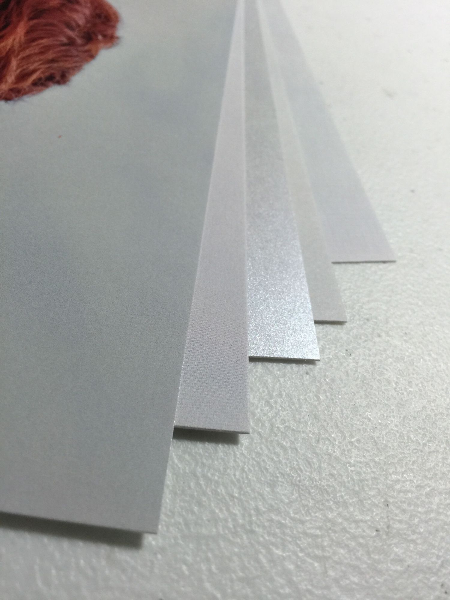 Several white and gray sheets of paper stacked and fanned out, showing different thicknesses and textures.