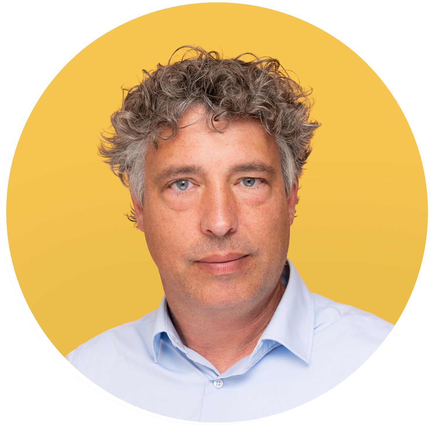 A man wearing a light blue button-down shirt poses against a bright yellow background in a professional headshot.