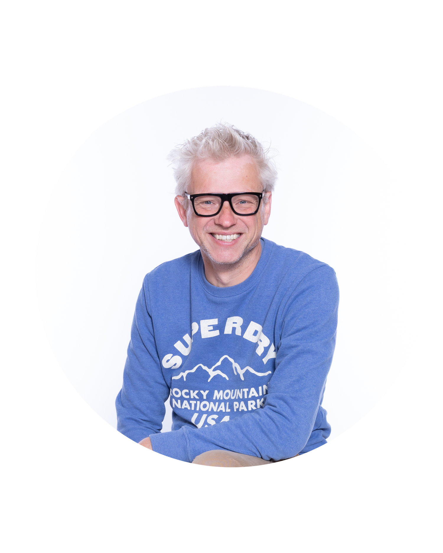 Individual wearing glasses and a blue sweatshirt with Rocky Mountain National Park text smiles at the camera.
