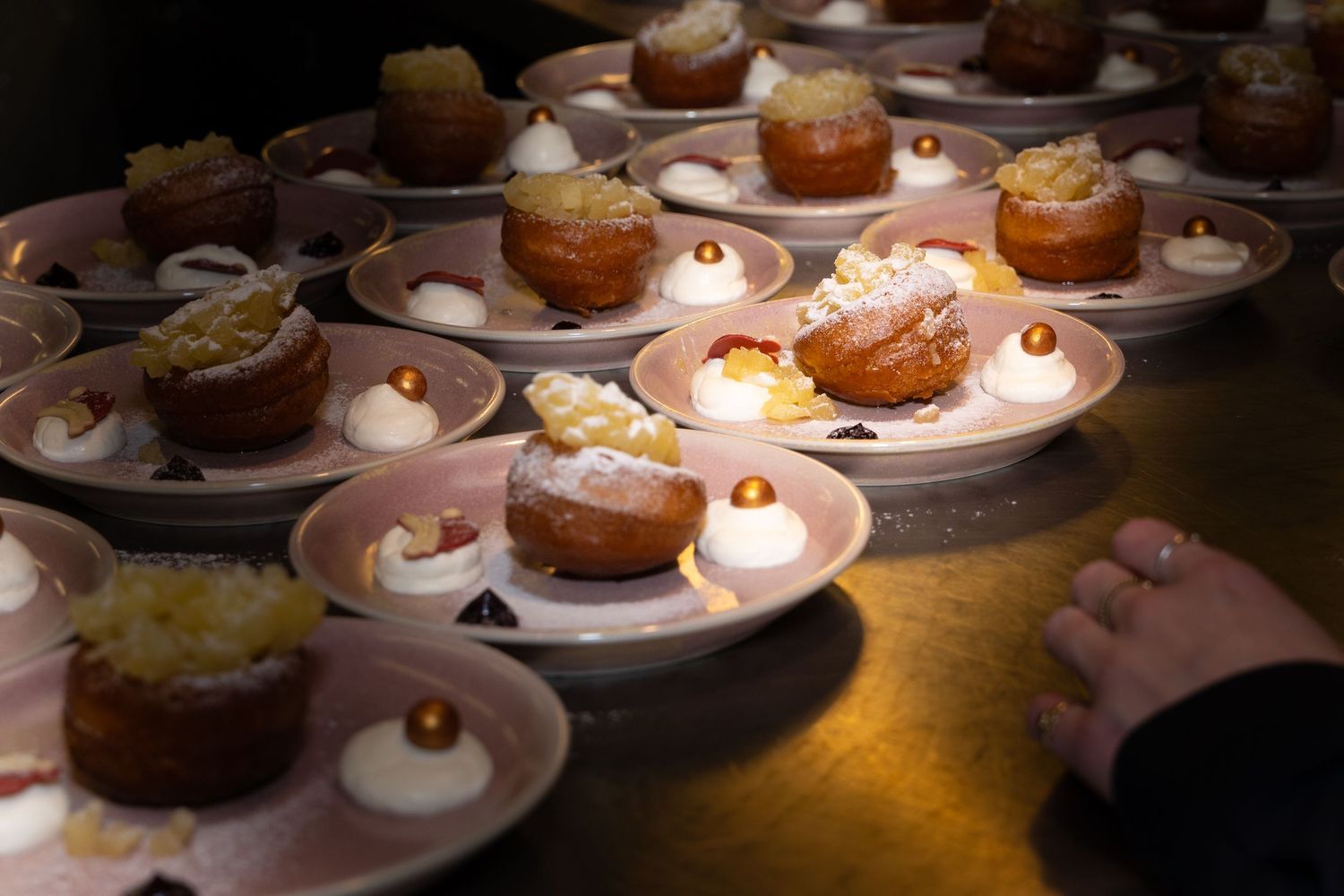 Rows of elegant plated desserts with mini cupcakes illuminated by small glowing tea lights creating an intimate ambiance.
