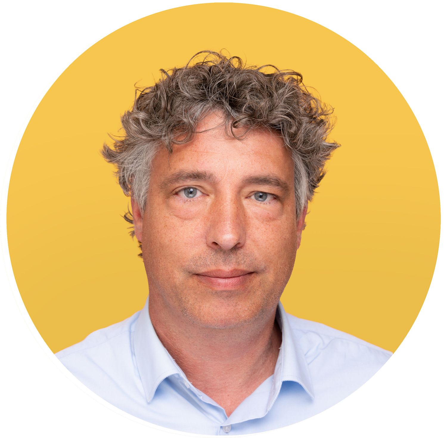 Professional headshot of a person with curly gray hair wearing a light blue button-down shirt against a yellow background.