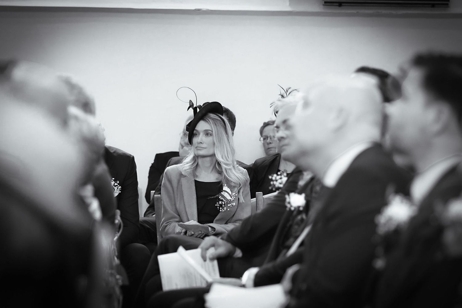 A black and white photo of wedding guests at a formal ceremony.