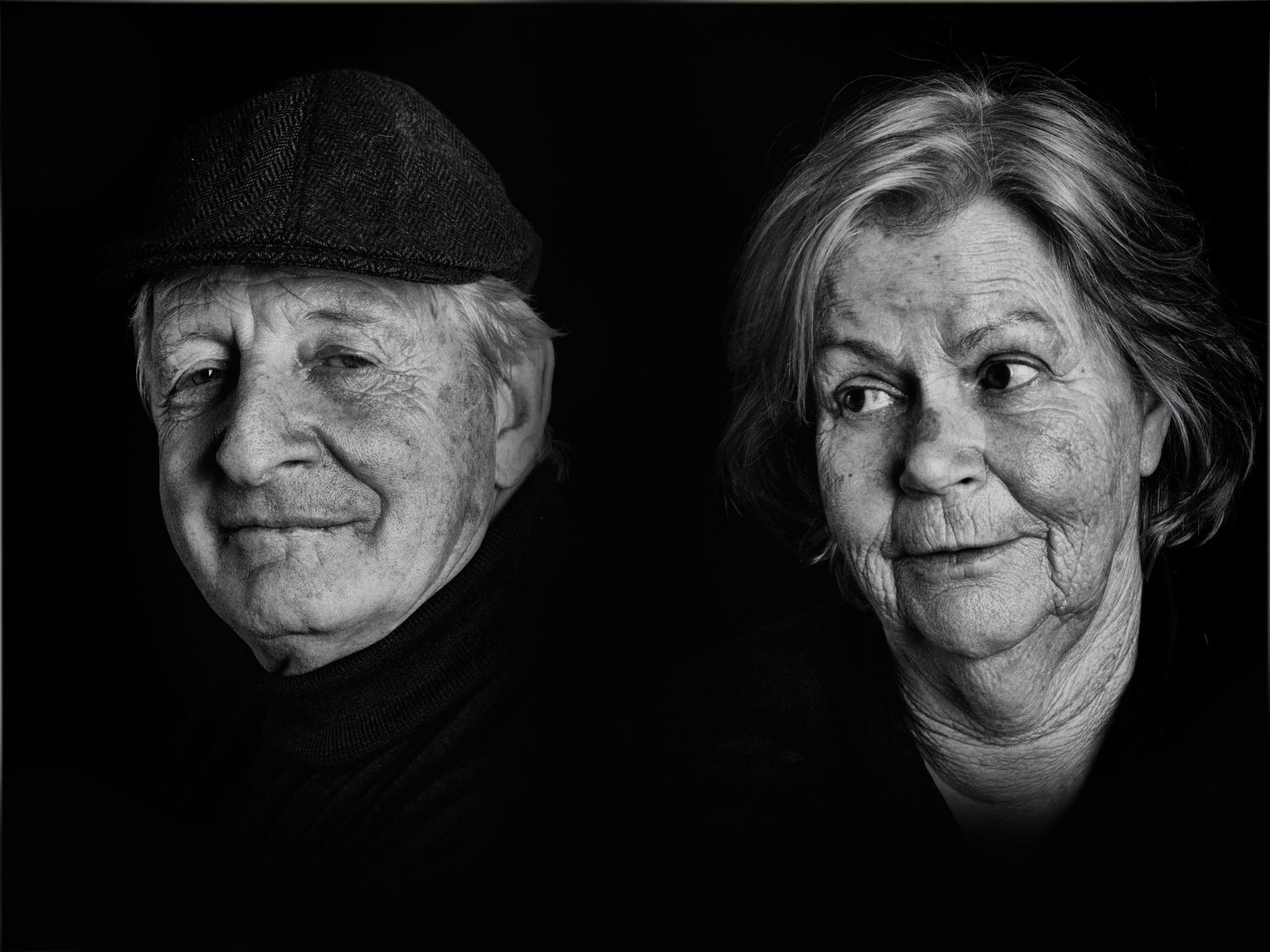 Dramatic black and white portrait of an elderly couple with artistic lighting and contrasting expressions.