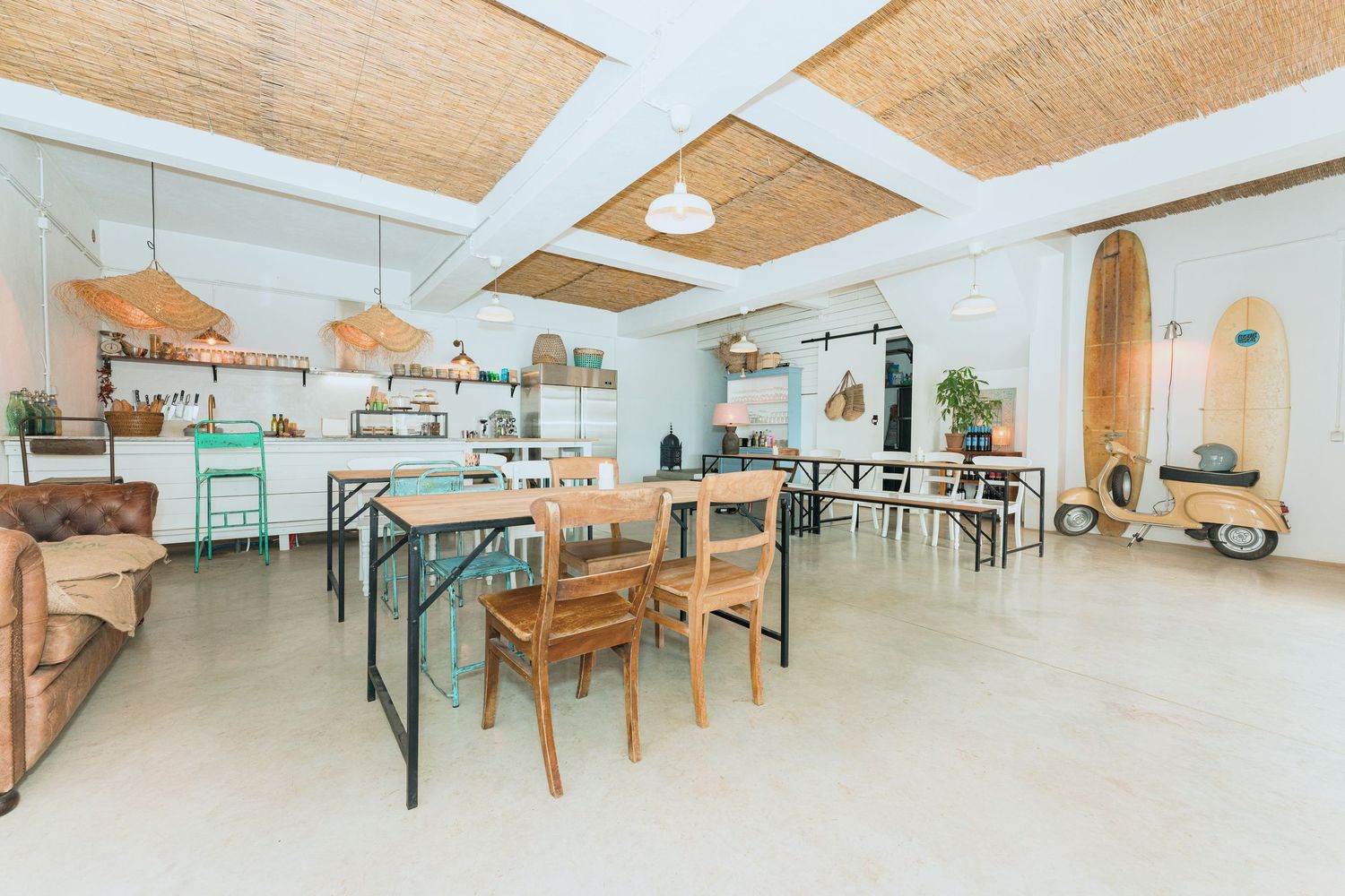 Modern dining space with wooden ceiling panels, green chairs and natural lighting.