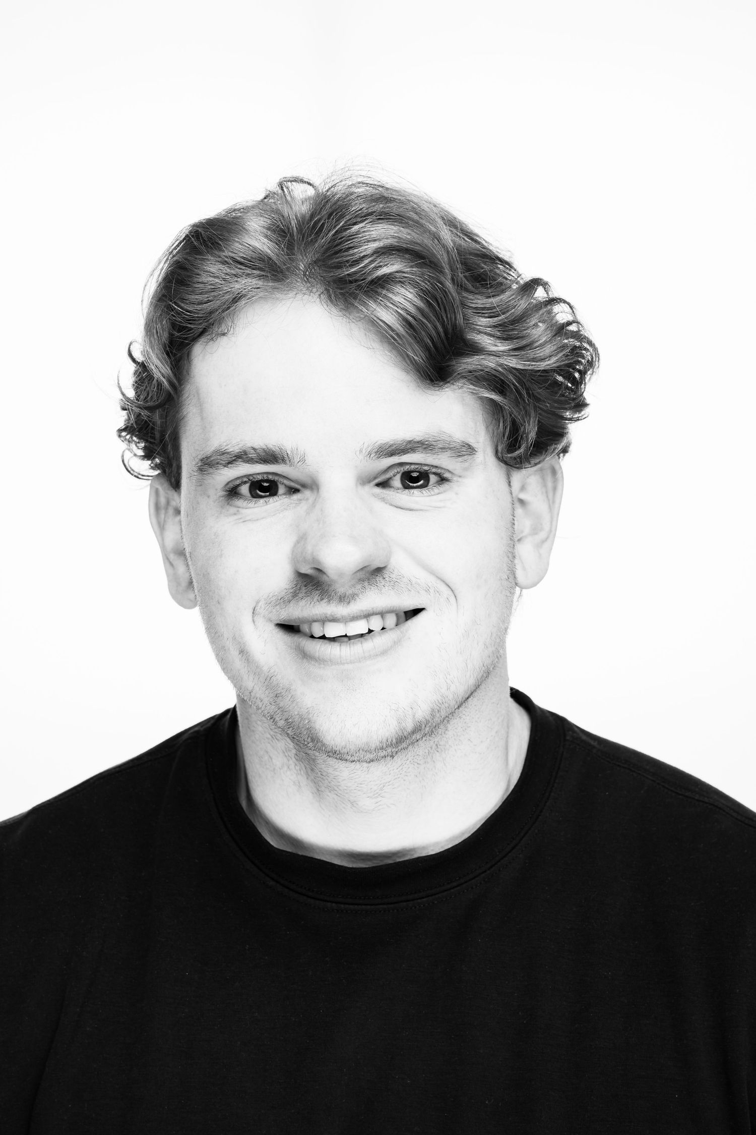 Black and white headshot portrait of a person in black shirt against white background.