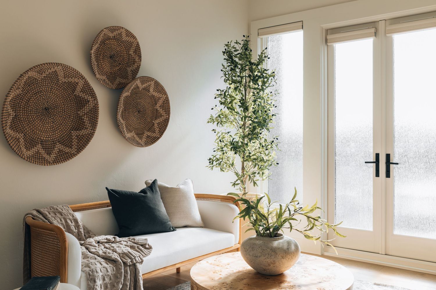Modern living room with decorative wood plates, indoor plant, and sofa near French doors.