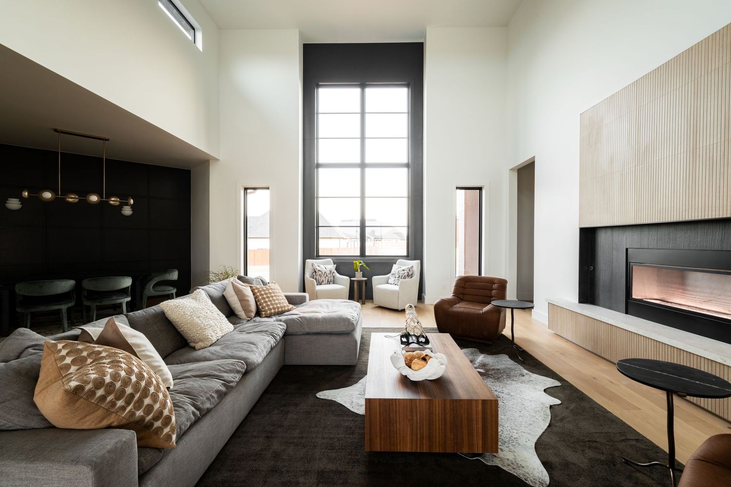 Modern living room with tall window, grey sectional sofa, wooden coffee table and wall-mounted entertainment unit.
