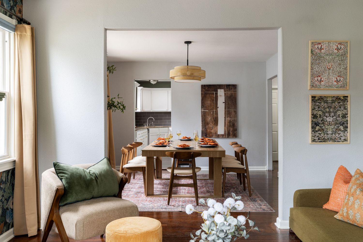 Cozy dining room with wooden table, green velvet sofa, pendant light, and modern boho home decor accents.
