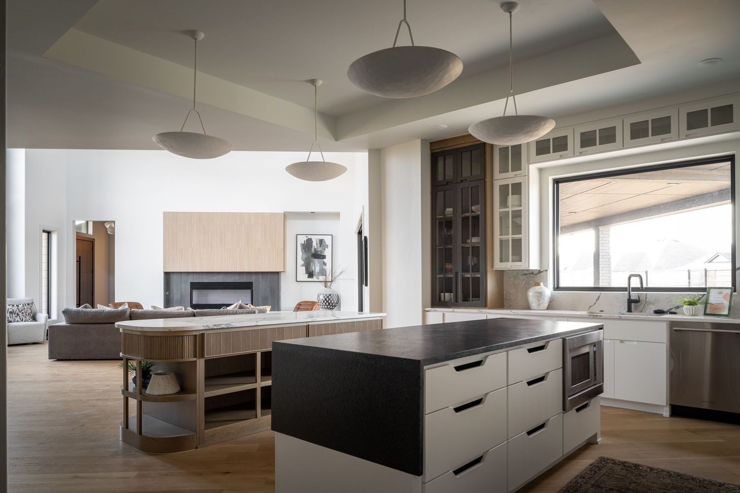 Modern open concept kitchen with dark wood cabinets, white countertops, pendant lights and large island on hardwood floors.