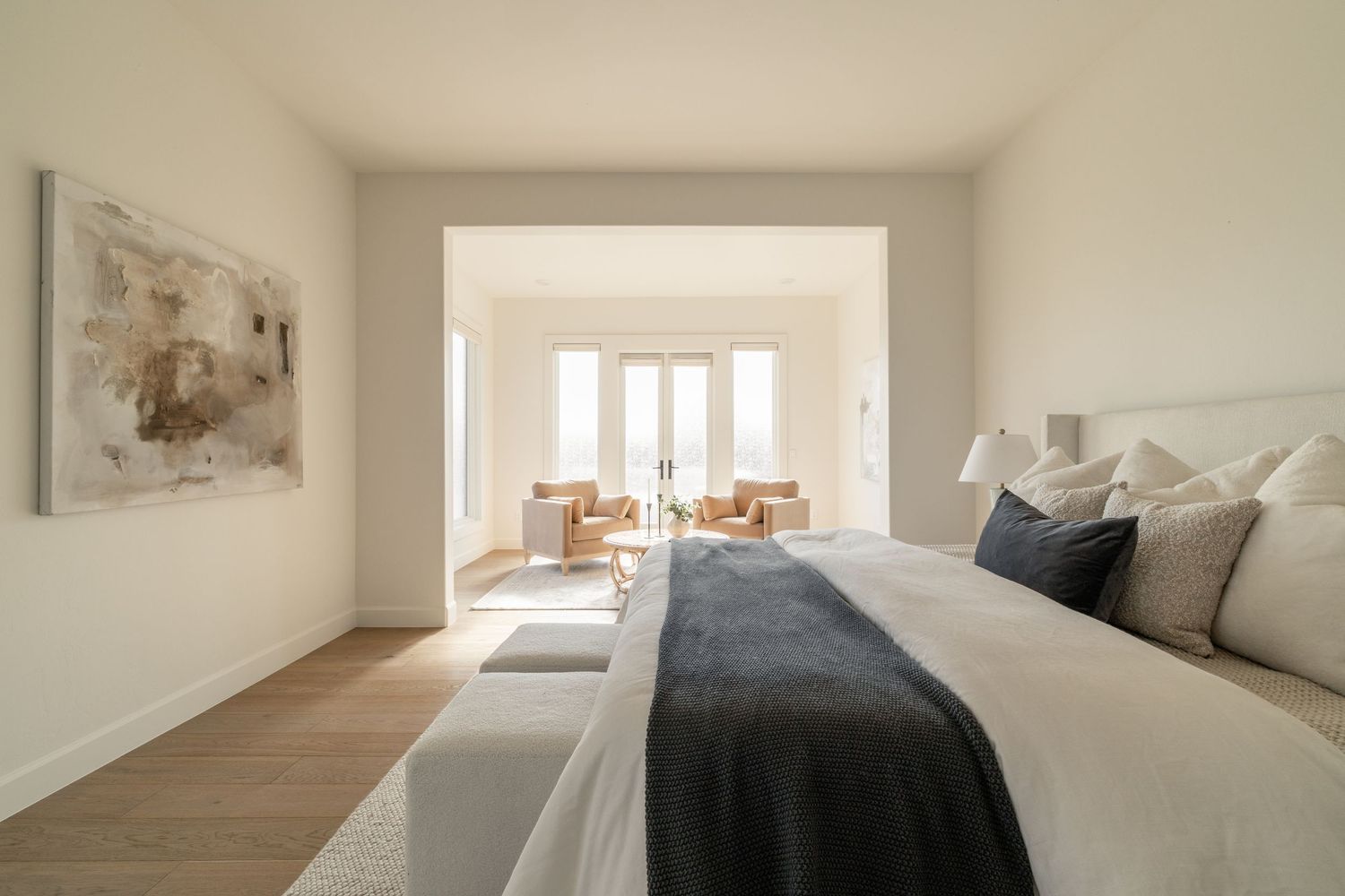 Spacious modern bedroom with bay windows, hardwood floors, and neutral color scheme.