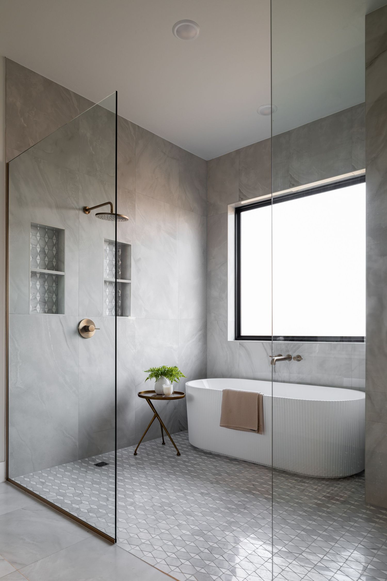 Modern bathroom featuring a freestanding tub, glass shower enclosure, and concrete walls with minimalist decor.