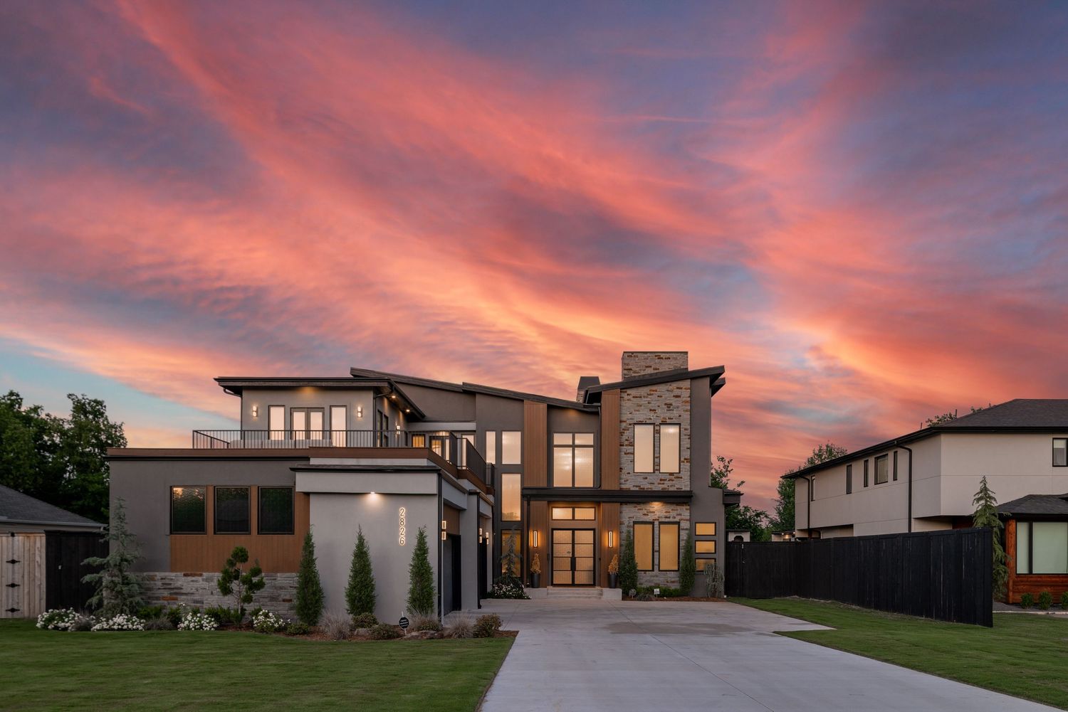 Modern luxury home exterior with dramatic sunset sky featuring contemporary architecture and clean lines.