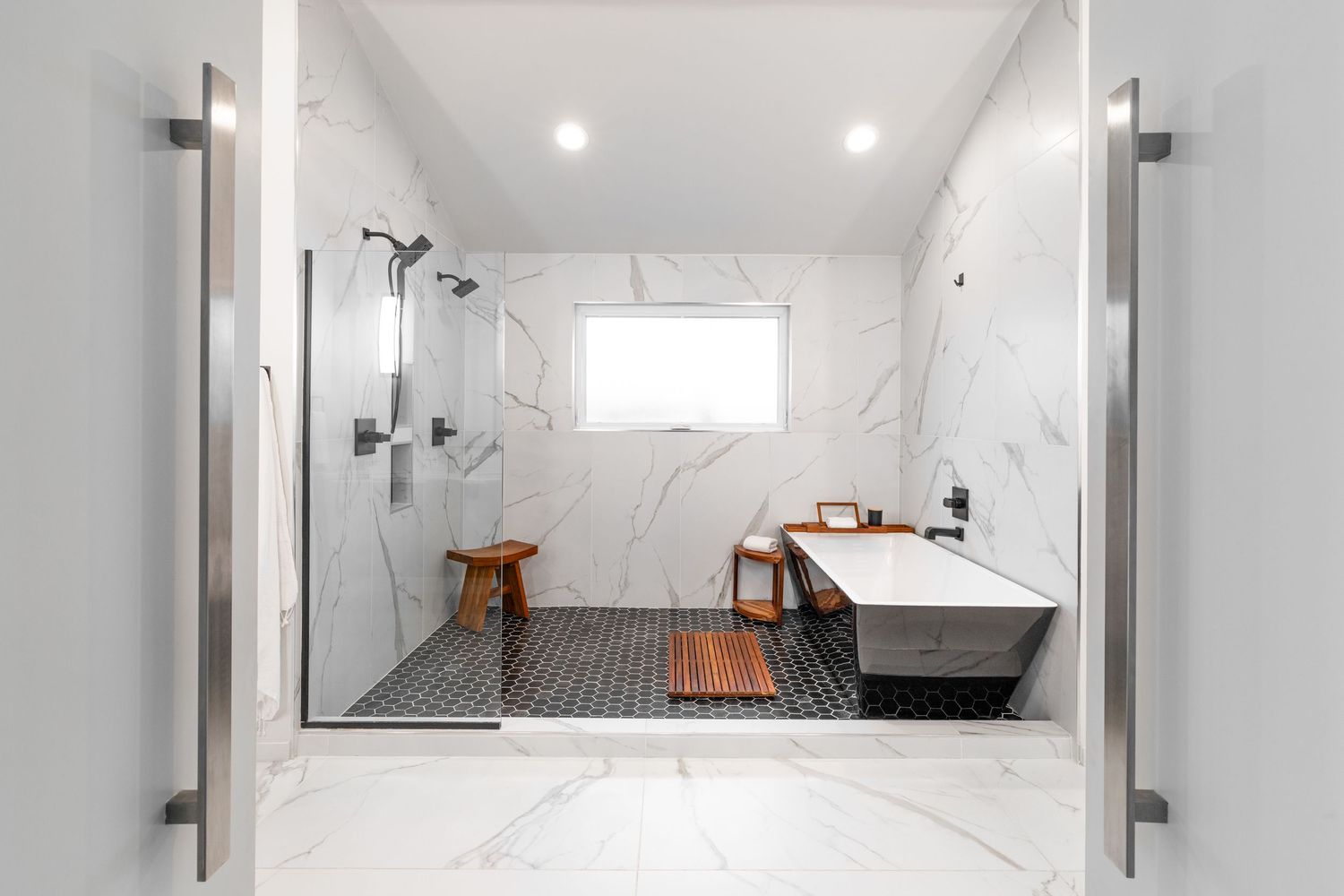 Luxurious spa-like bathroom featuring marble walls, wooden accents, and black tile flooring with modern fixtures.