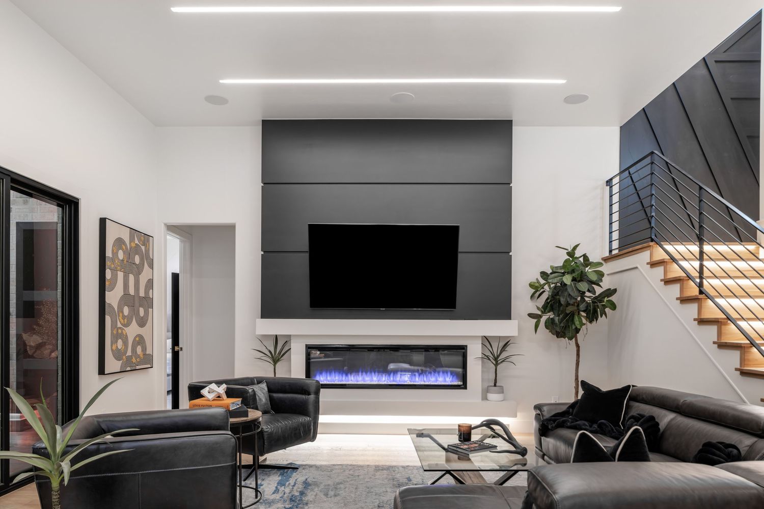 Modern minimalist grey and white living room interior with wall mounted TV and wooden stair railings.