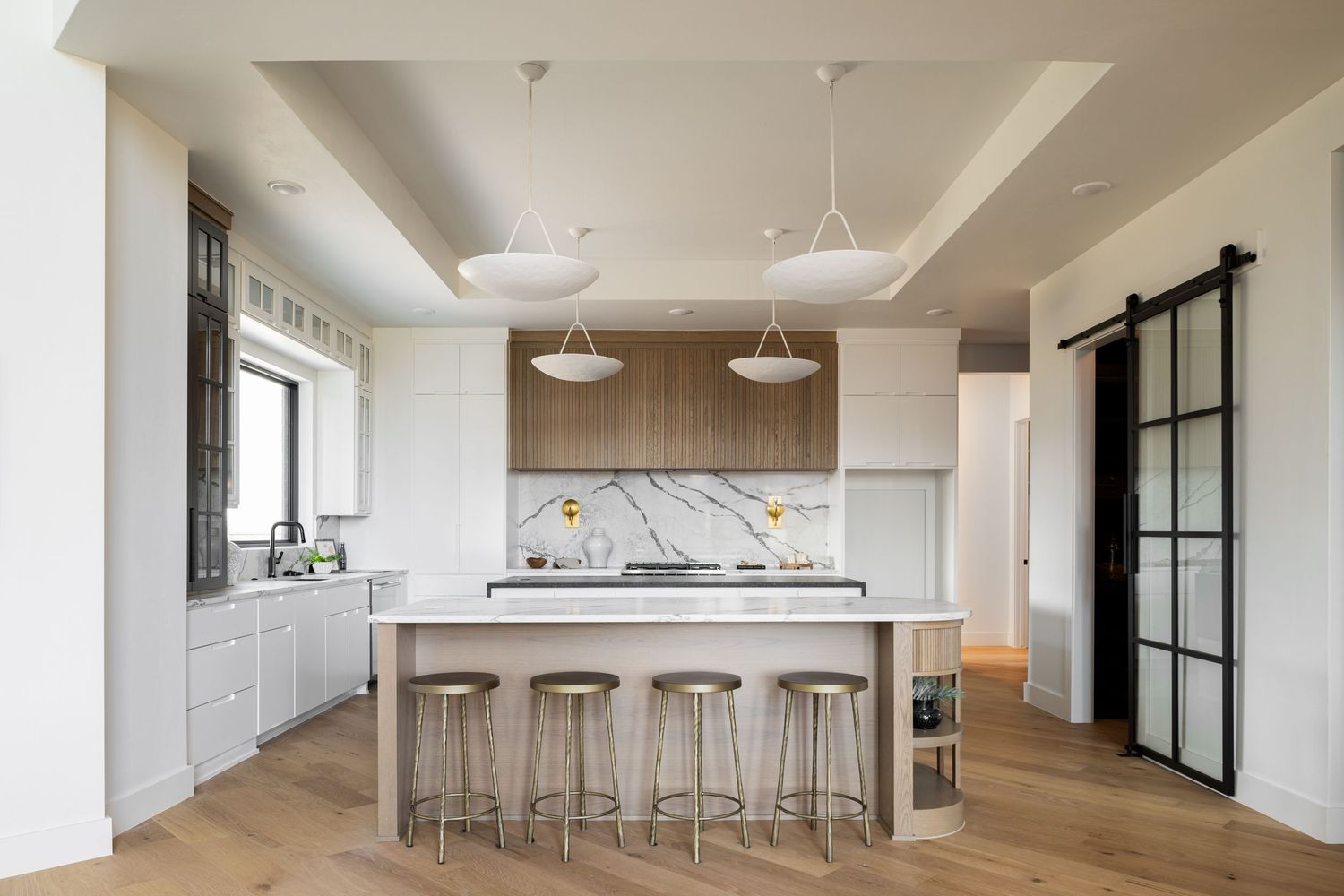 Modern open-concept kitchen with white cabinetry, marble countertops, and pendant lighting in a bright interior space.