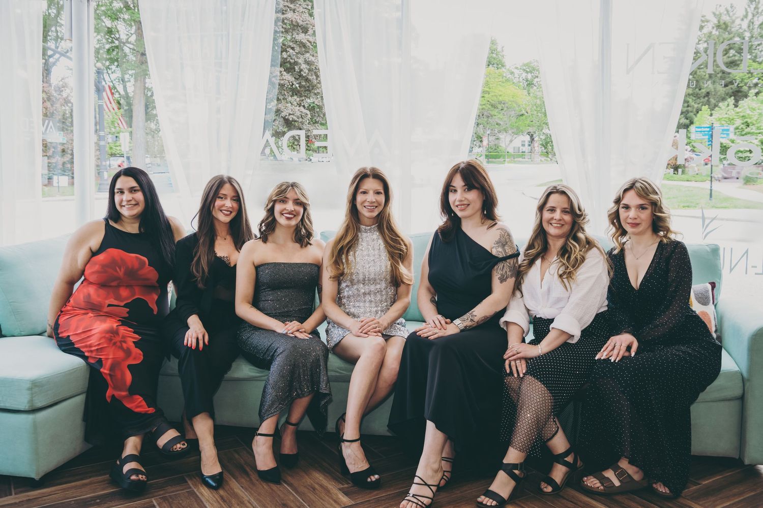 Group of women sitting together on a blue couch in elegant dresses for a special occasion.