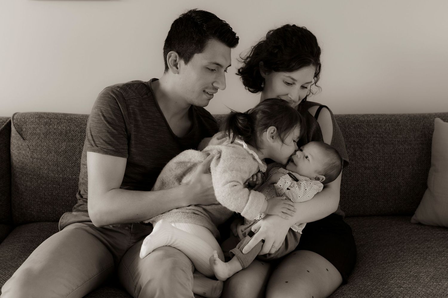 A family sitting together on a couch in a tender black and white moment at home.