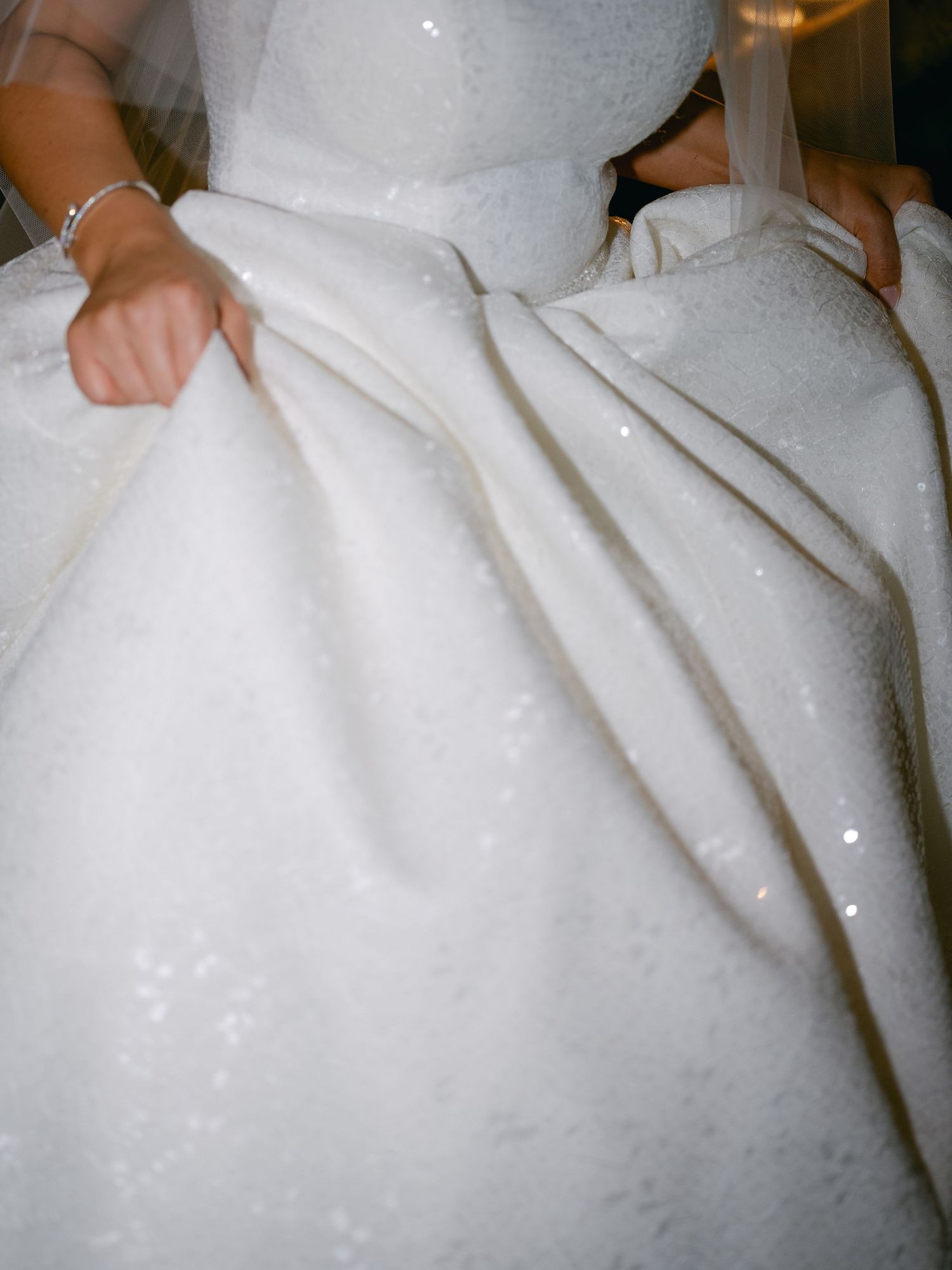 Close-up detail of a white wedding dress showing the fabric's texture and elegant draping.