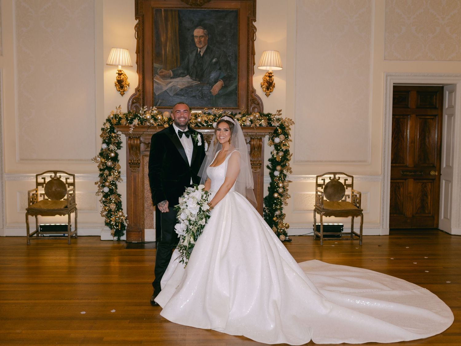 Bride in flowing white wedding dress with long cathedral train walking through an elegant ballroom hallway.