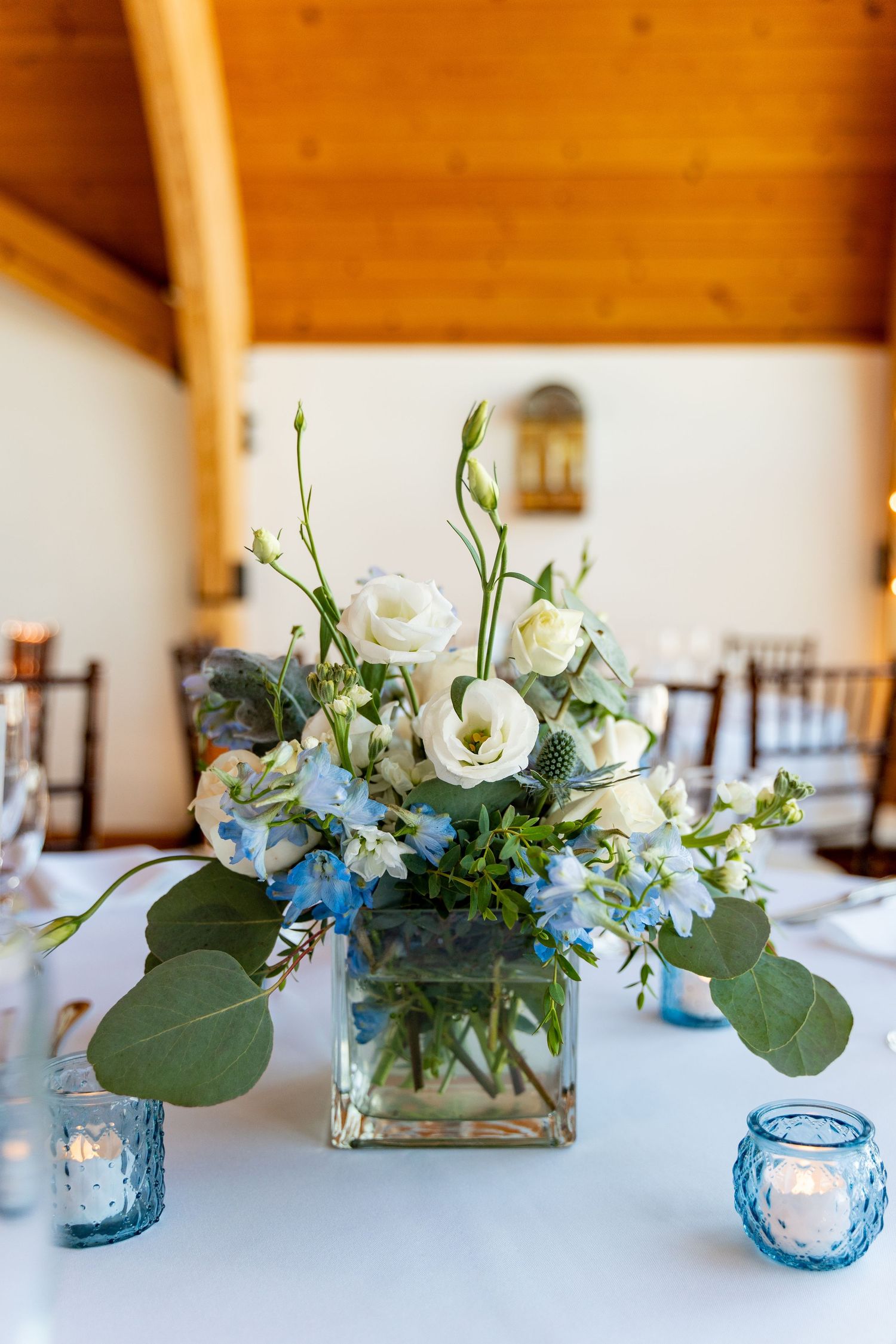 Elegant blue and white floral centerpiece with eucalyptus in glass vase.