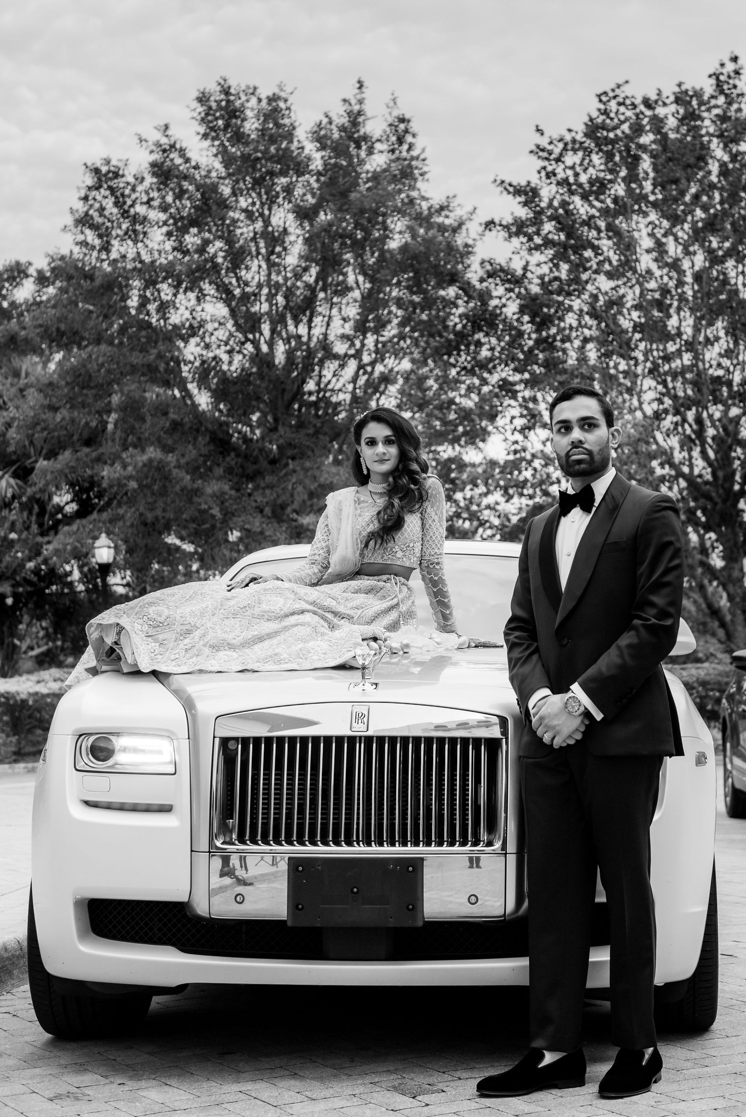 Elegant couple posed with white Rolls Royce, black and white photography.