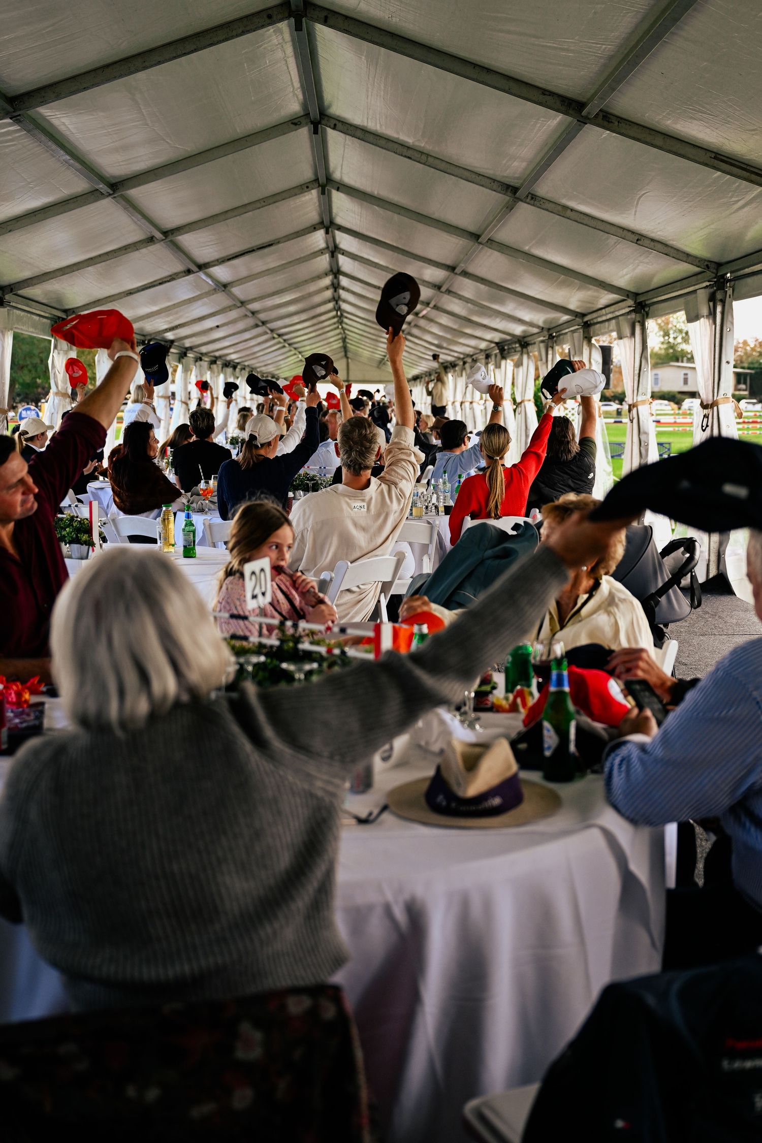 Large event tent filled with tables and guests celebrating at a festive gathering.