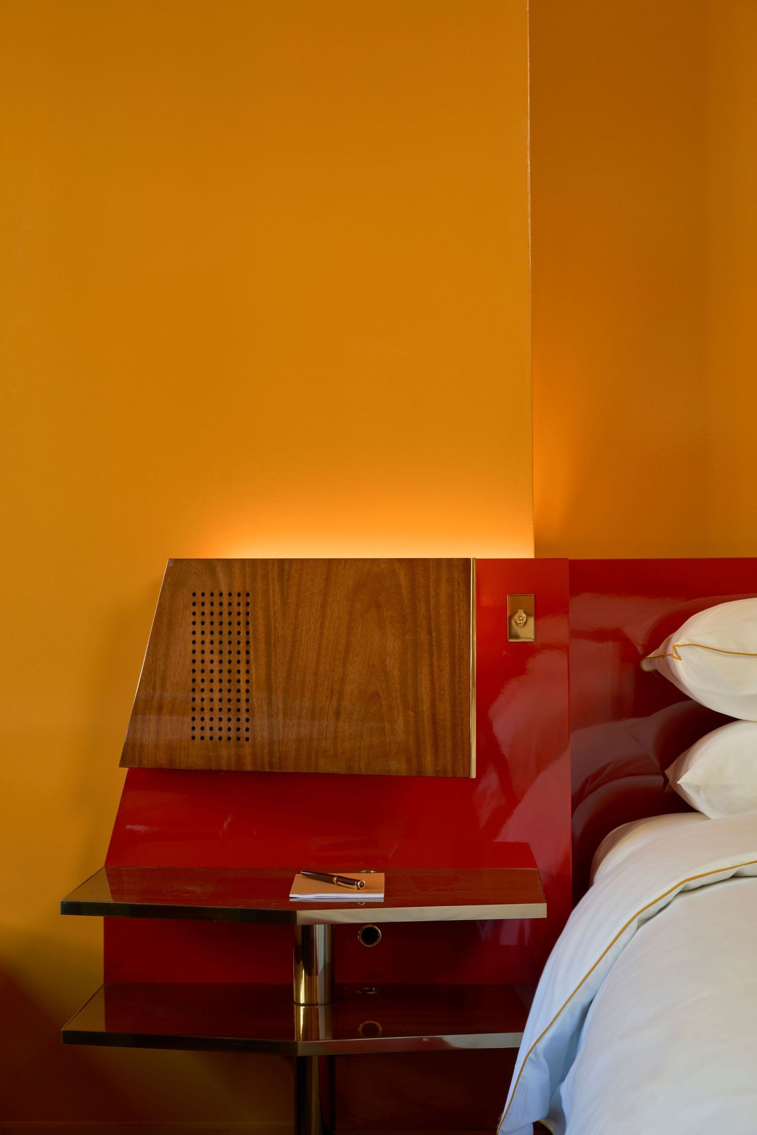 Detail of the headboard in the guestroom of The Manner hotel in downtown NY. Red millwork and yellow wall.