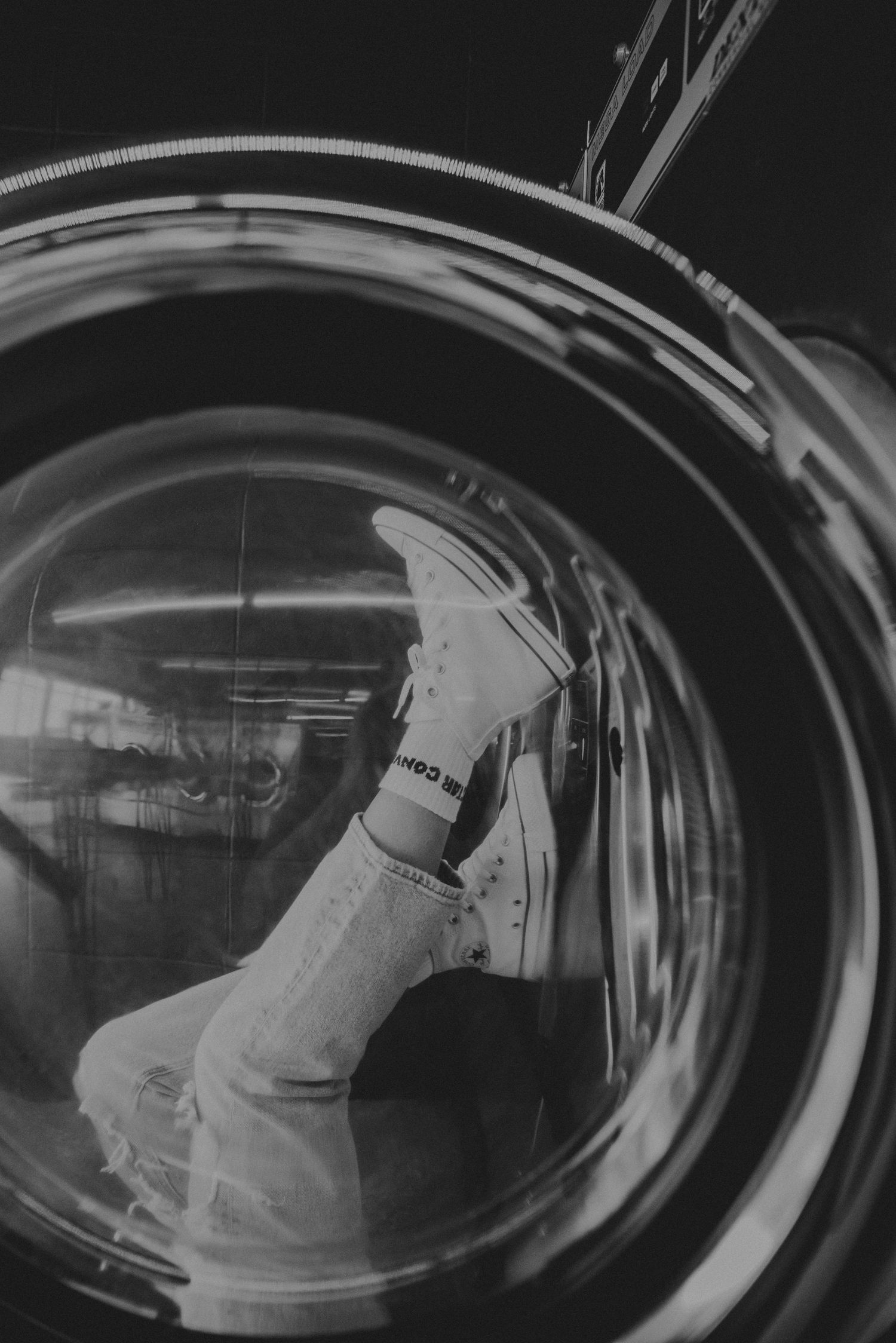 Black and white view of an astronaut suit reflected in curved glass of a space capsule window or helmet visor.